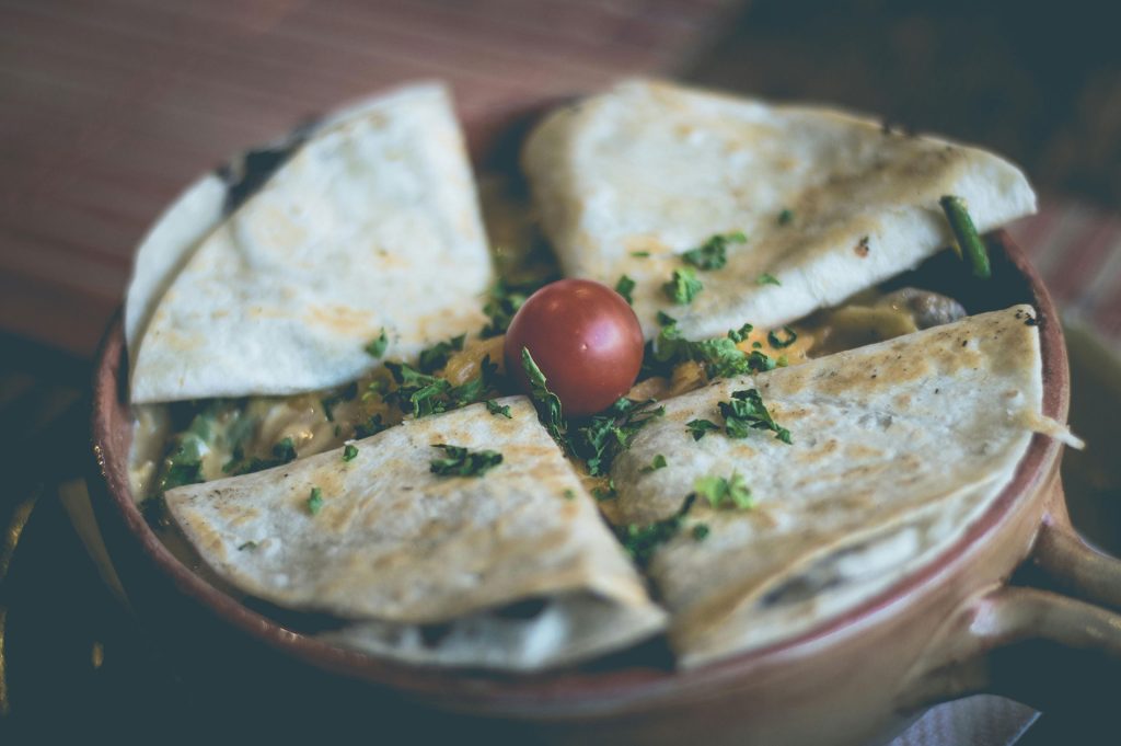 Quesadilla on round plate with tomato and garnish
