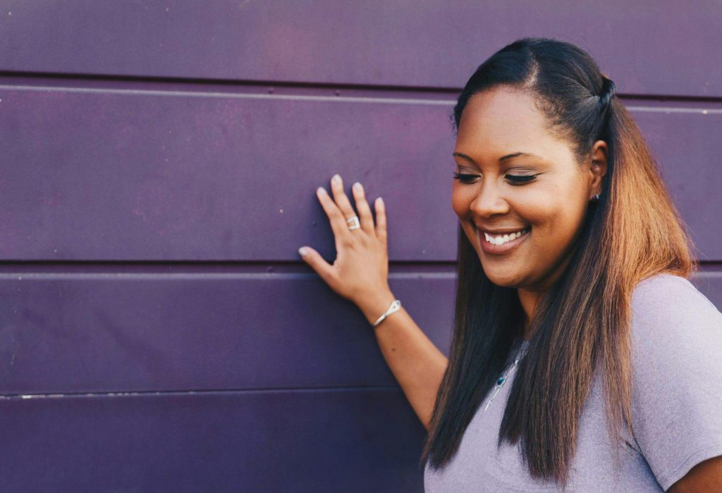 Smiling woman standing next to purple wall
