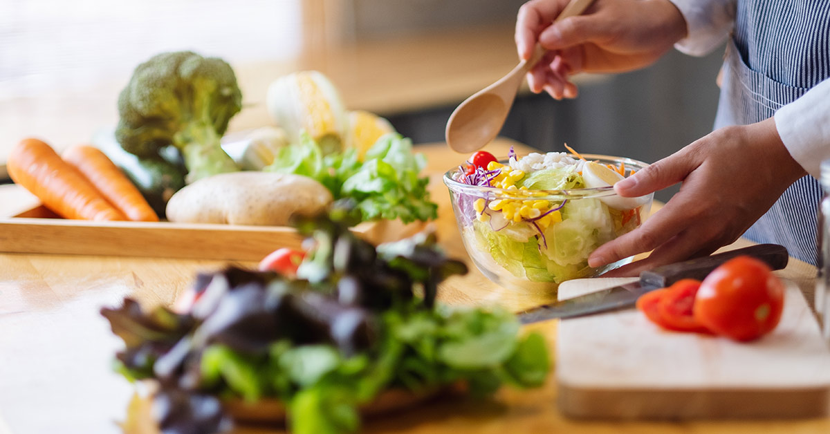 Person mixing vegetables in bowl