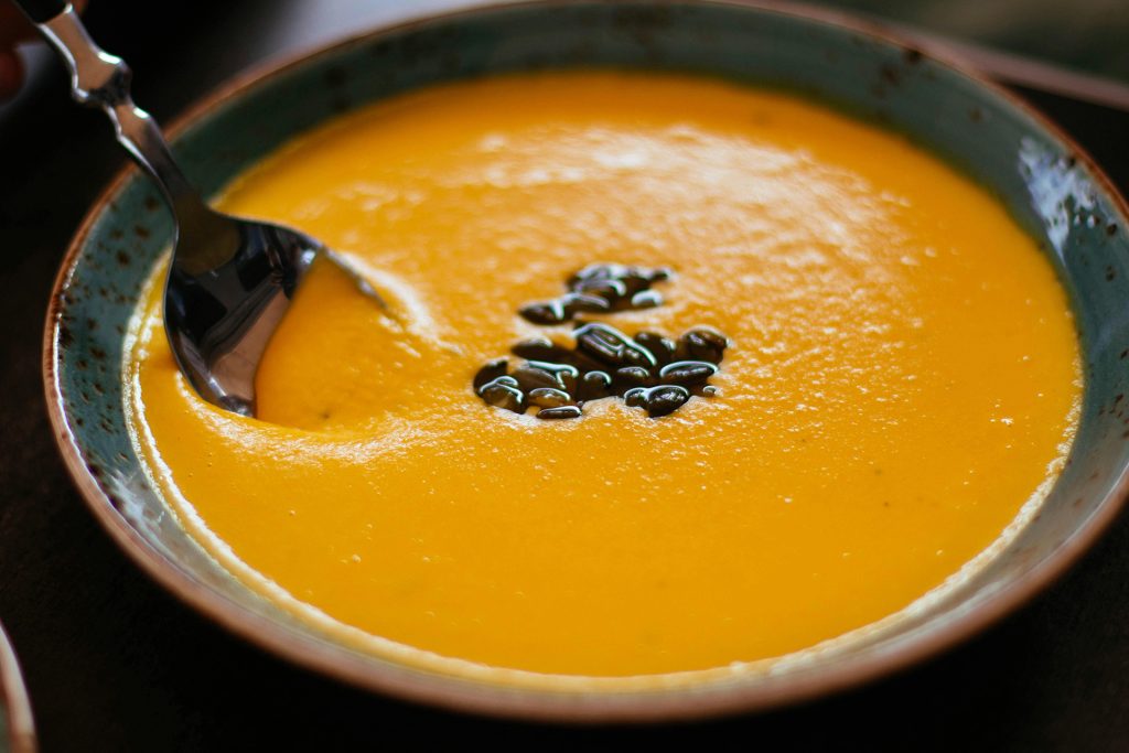Close up of pumpkin soup bowl with spoon in it