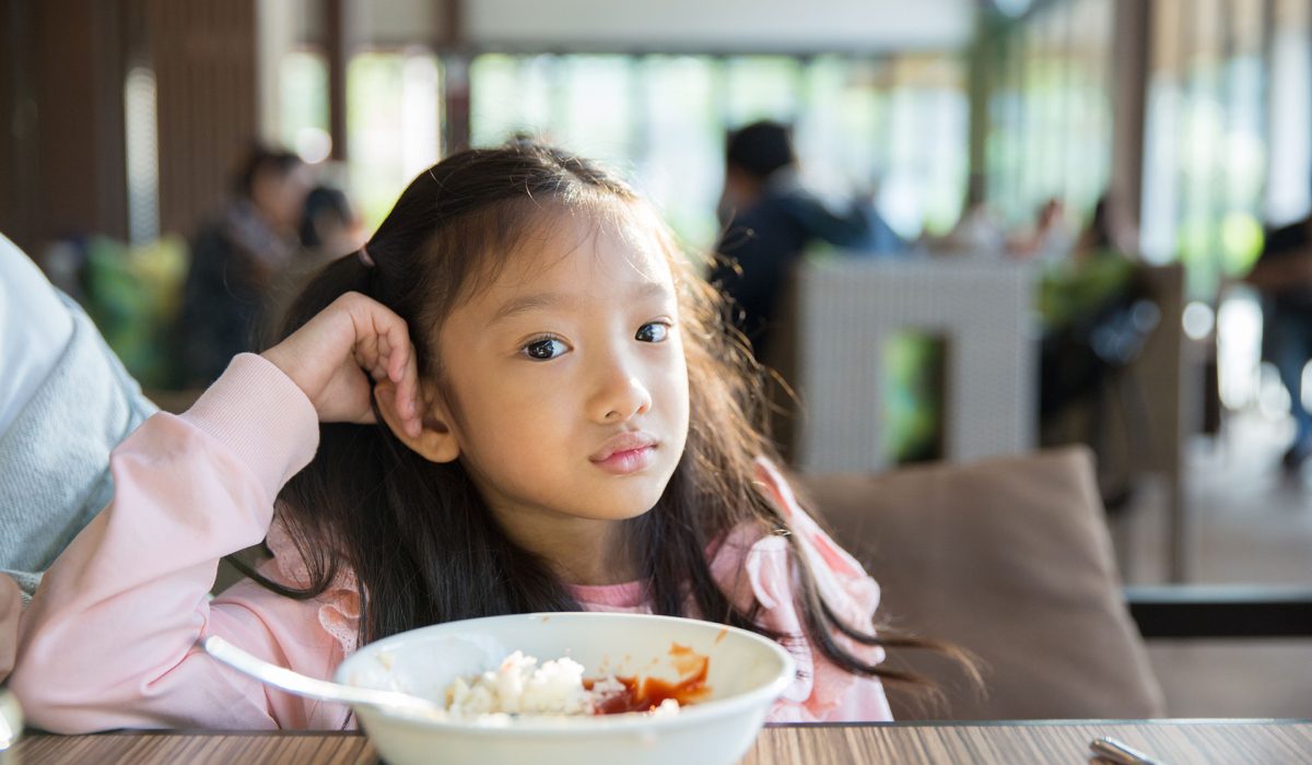 Young girl refusing to eat bowl of food.