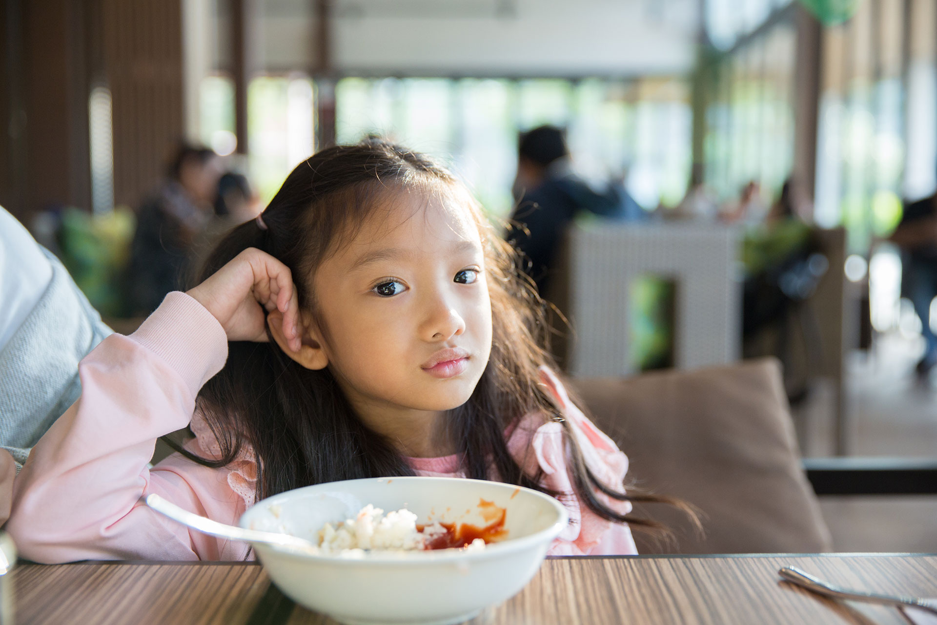Young girl refusing to eat bowl of food.