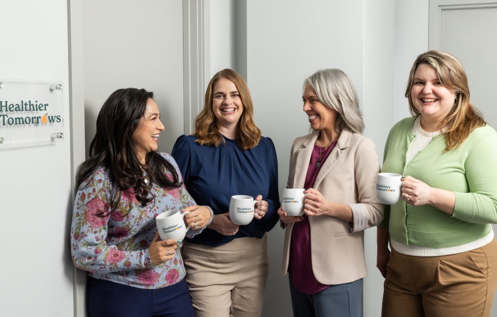 Group of woman standing holding coffee mugs