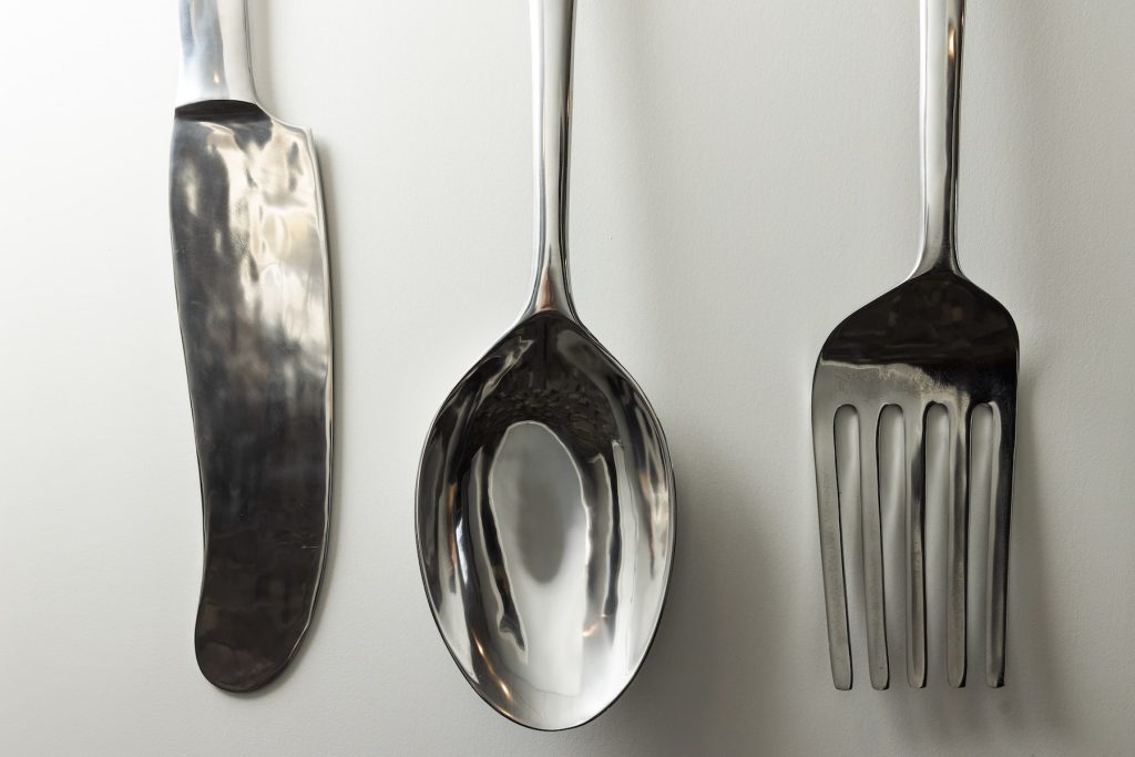 Oversized utensils hanging on a wall — supporting recovery the day after binge eating with compassion, not restriction